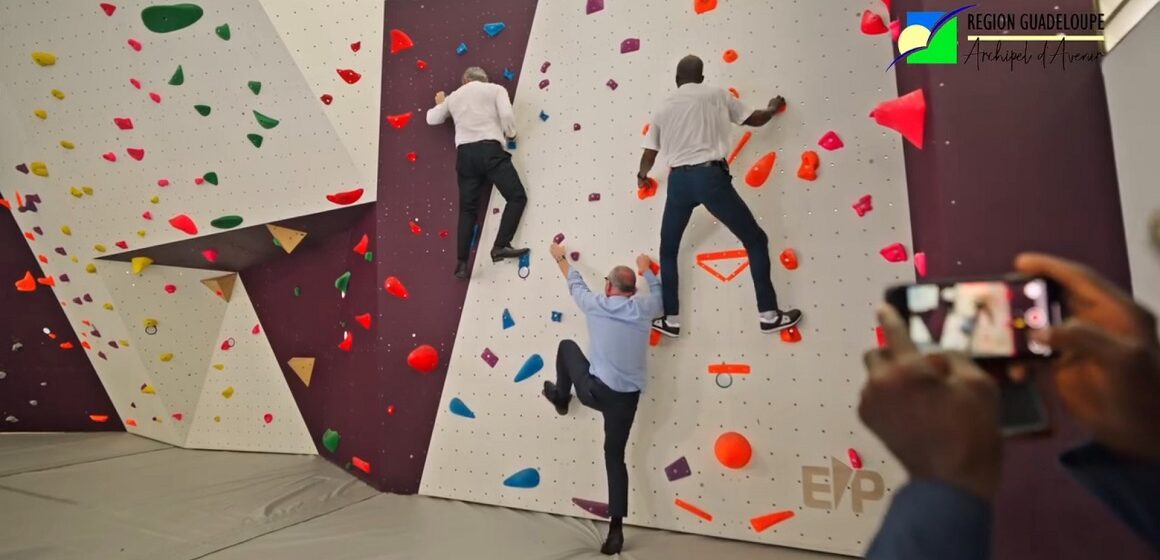 Ce mercredi 9 juillet 2025, de gauche à droite, le recteur Gabriele Fioni, le préfet Xavier Lefort, le président de Région Ary Chalus, se prêtent à tester le mur d’escalade d’un des gymnases inaugurés au sein du lycée Baimbridge. Photo : capture écran vidéo Région Guadeloupe.