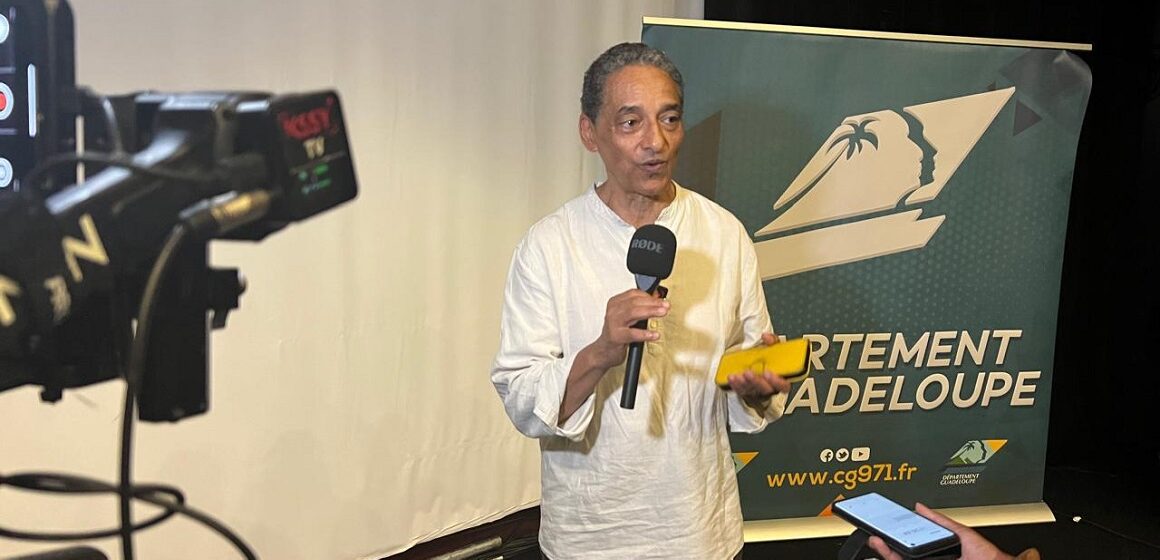 Serge Romana, président du Comité de la marche du 23 mai 1998 et coprésident du comité de pilotage du futur Mémorial national des noms des victimes de l’esclavage colonial, présente le 23 décembre 2025 au Mémorial Acte à Pointe-à-Pitre, les plans architecturaux et paysagers du projet. Photo : Le Courrier de Guadeloupe